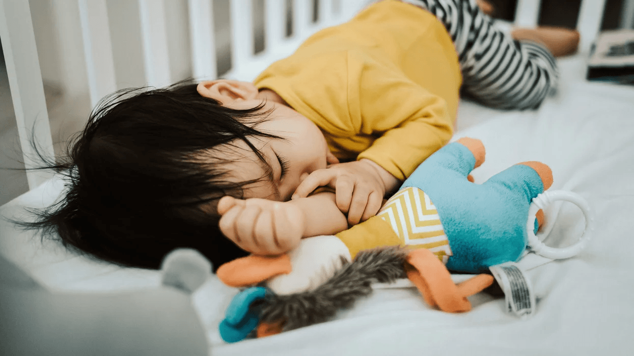 baby sleeping in a crib with toys