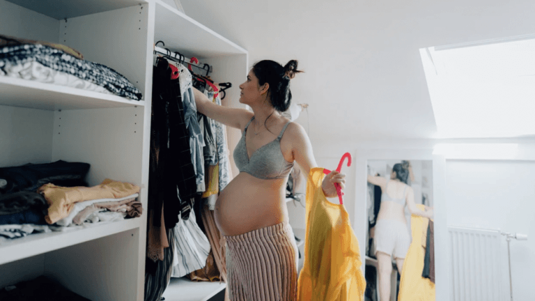 pregnant woman picking out clothes in a closet