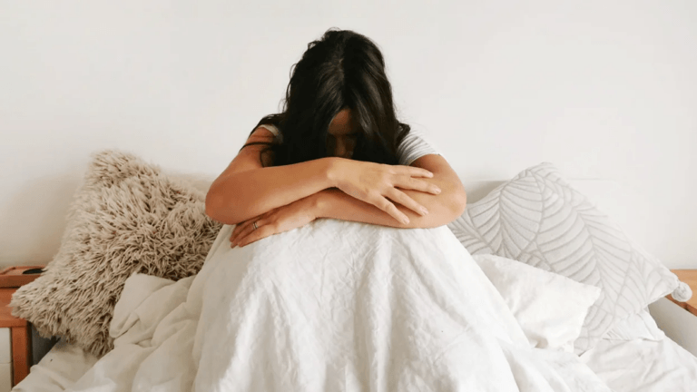 mom hugging knees sitting in bed