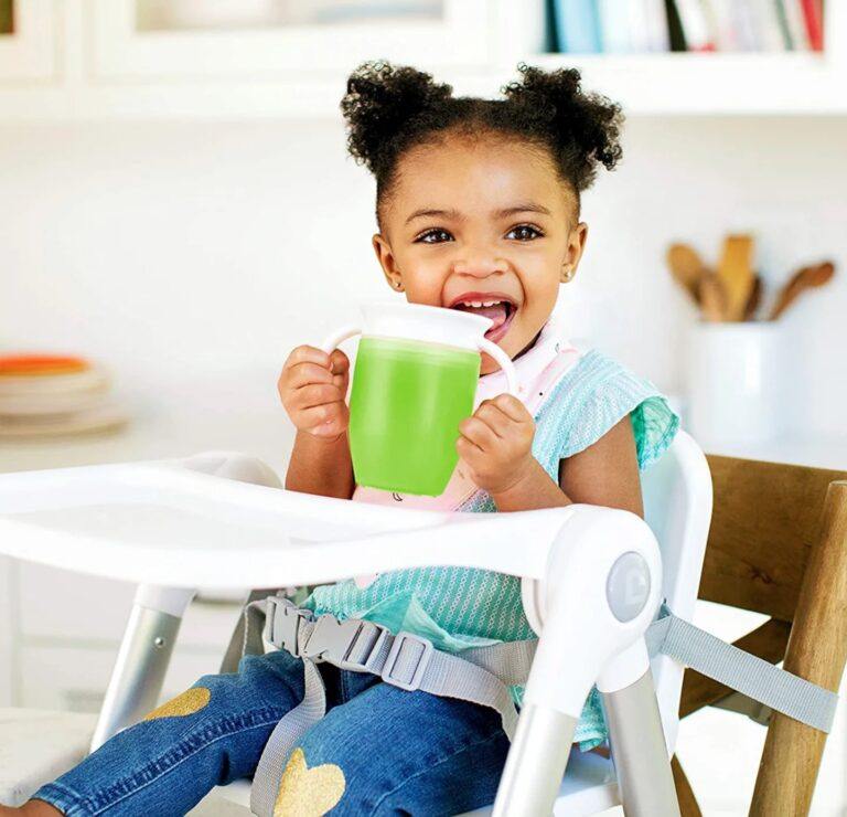 little girl drinking from a sippy cup in her high chair