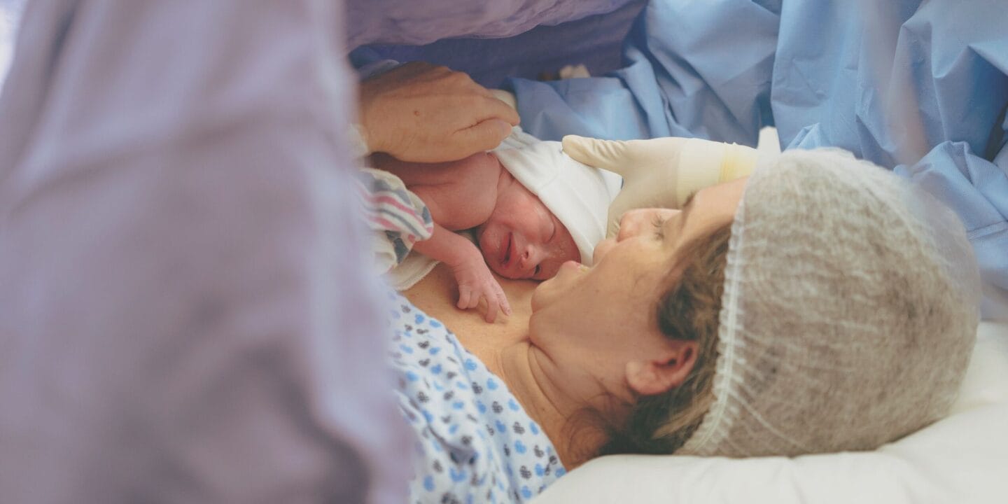 Mother holding infant after c-section birth showing what happens during a c-section delivery