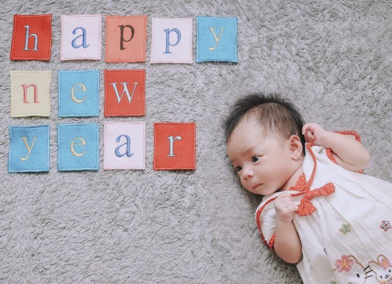 newborn lying next to blocks that spell 'happy new year'- january babies