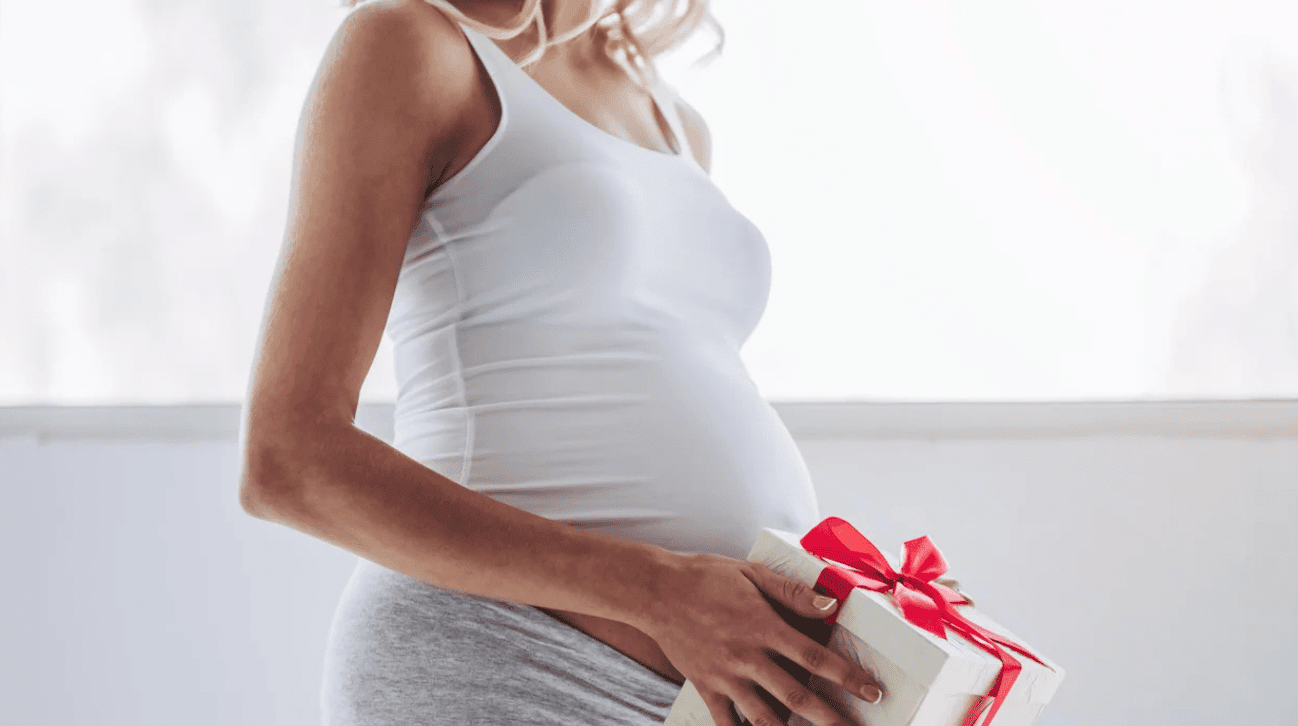 pregnant woman holding a gift in front of her belly