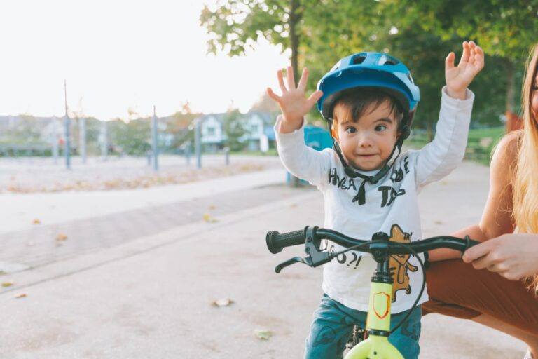 little boy wearing a helmet and riding a balance bike