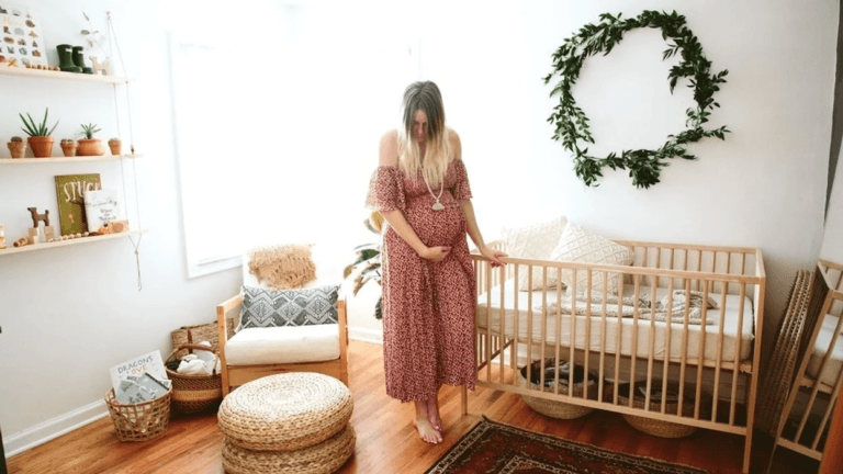 woman holding her belly standing in a nursery