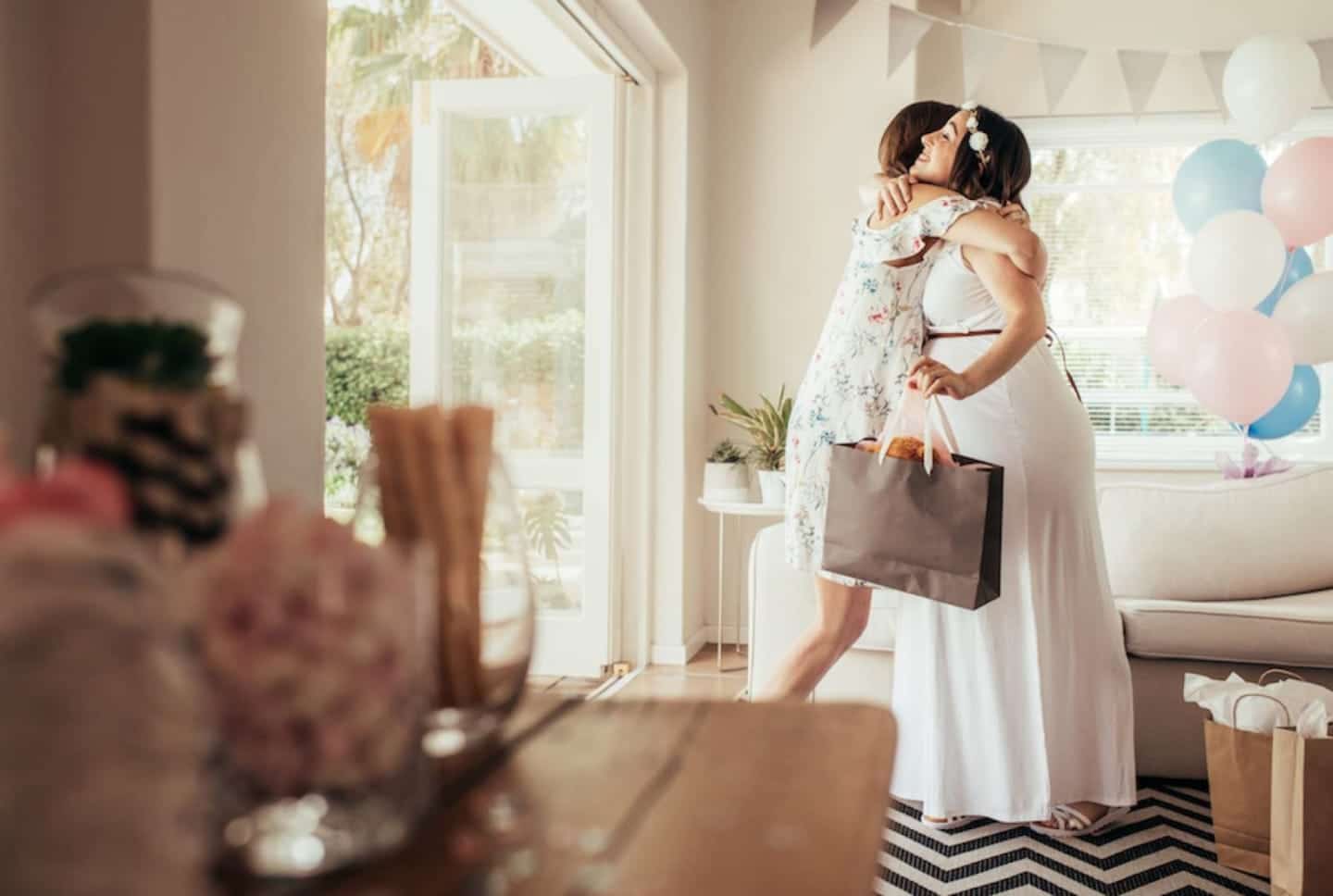 pregnant woman hugging another woman and holding a gift