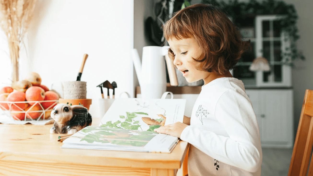 little girl reading a book at the table