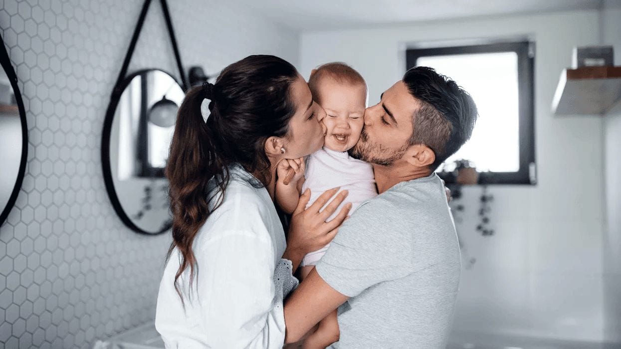 parents kissing baby on the cheeks