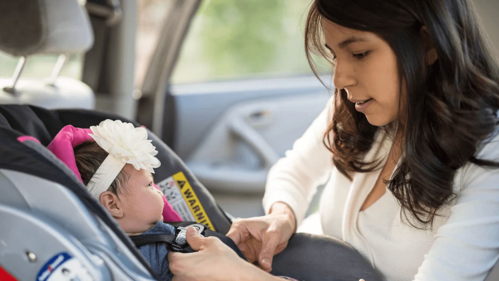 mom helping baby in a car seat - child safety