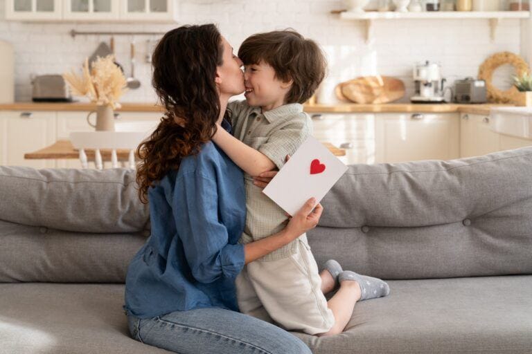 mom kissing highly sensitive child on cheek holding a handmade card