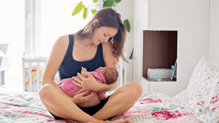 mother breastfeeding baby on a bed