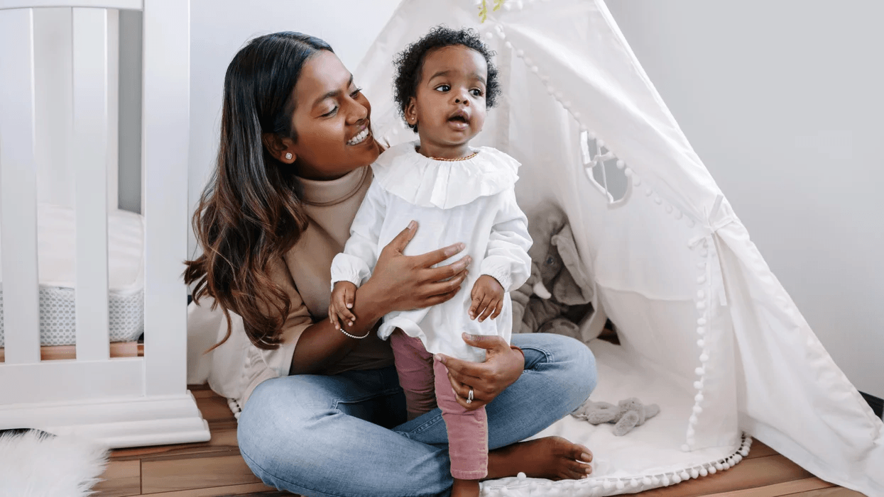 mom sitting with toddler in front of a tent