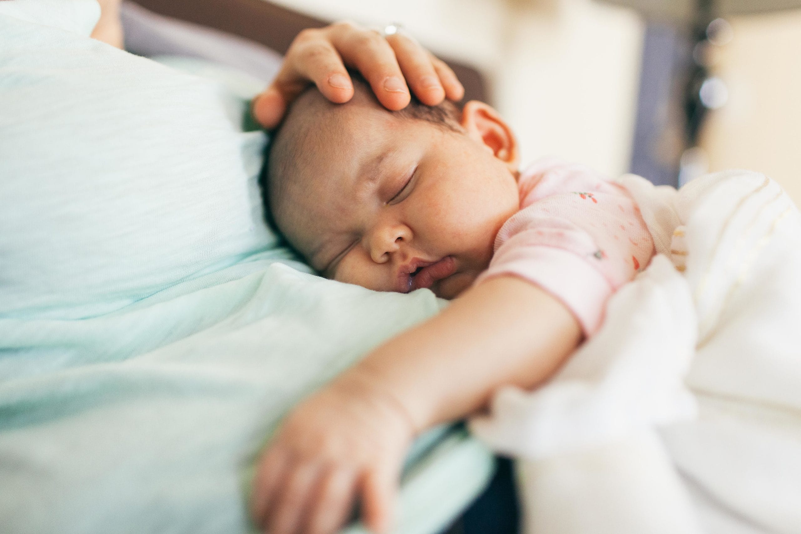 mom holding a sleeping newborn baby on her chest while thinking about rules for visiting a newborn