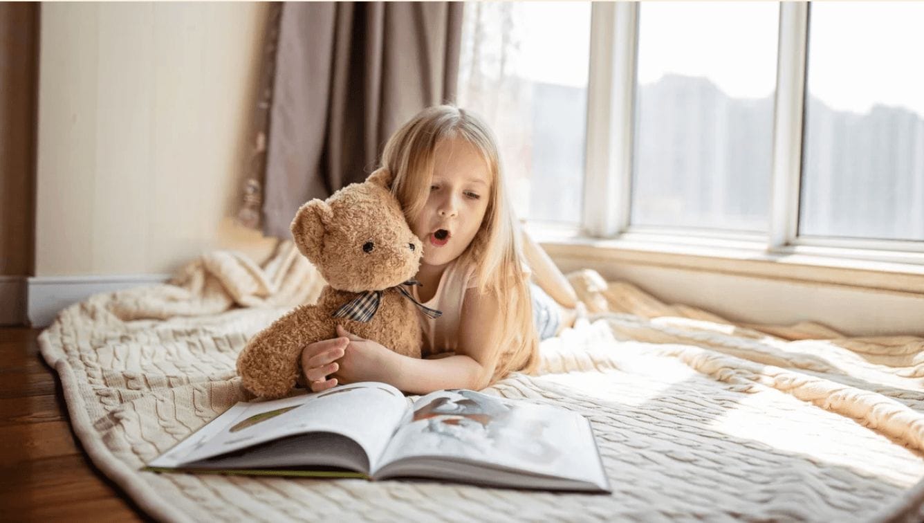 little girl reading on a bed