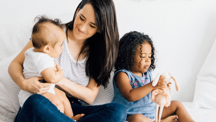 mom holding a baby while a toddler sits on her lap