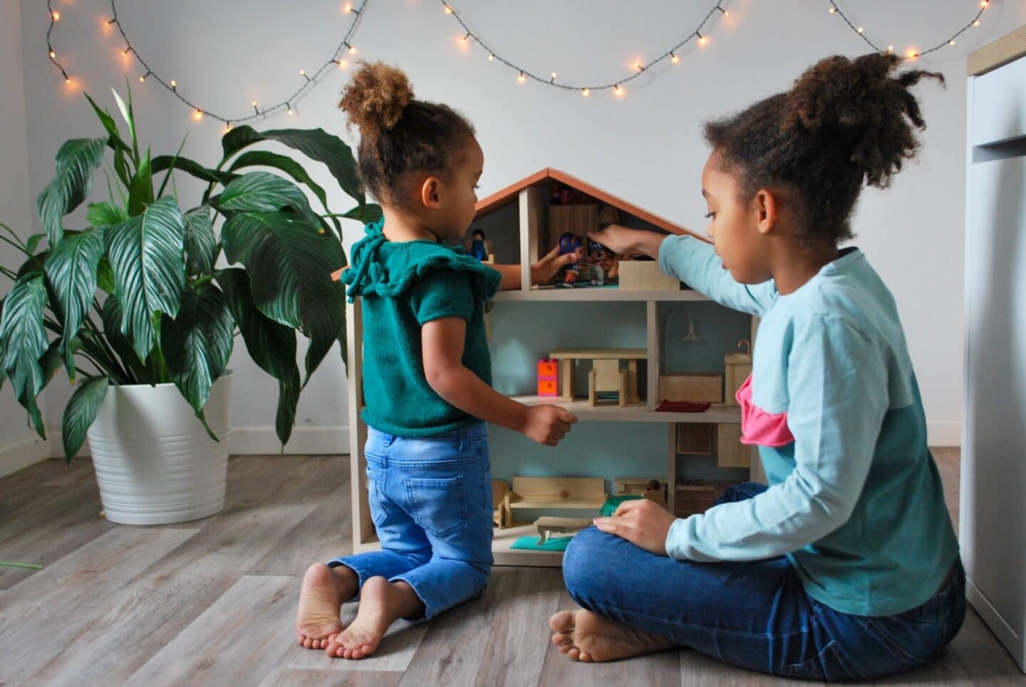 two girls playing with a dollhouse