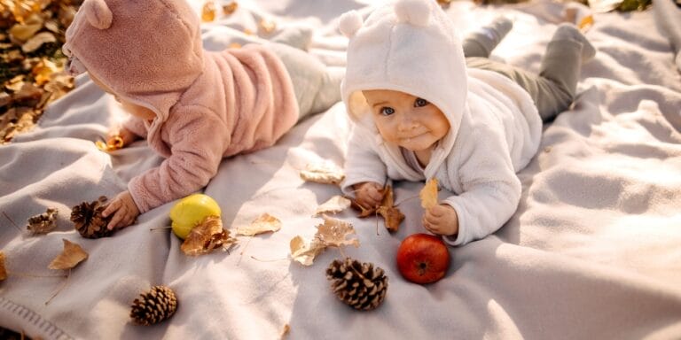 two babies outside on blanket in fall - fall baby names