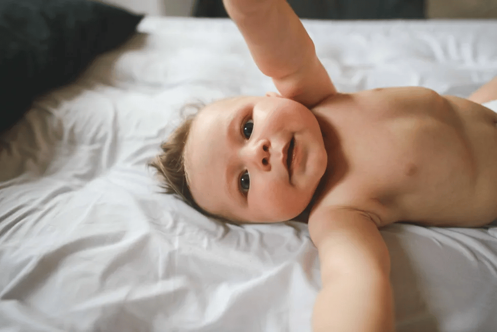 cute baby laying on back and reaching towards mama, one of the 5 month milestones