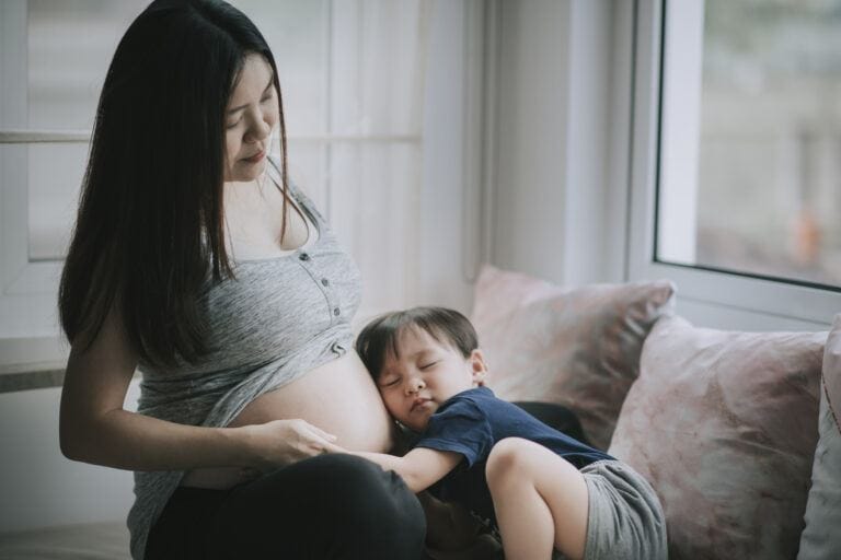 ready for a second baby: toddler rests head on mother's pregnant belly