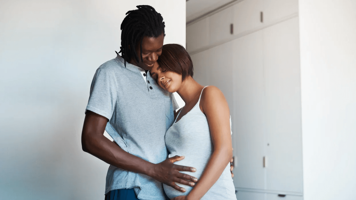 African American dad holding moms pregnant belly, smiling because they found the best birth class