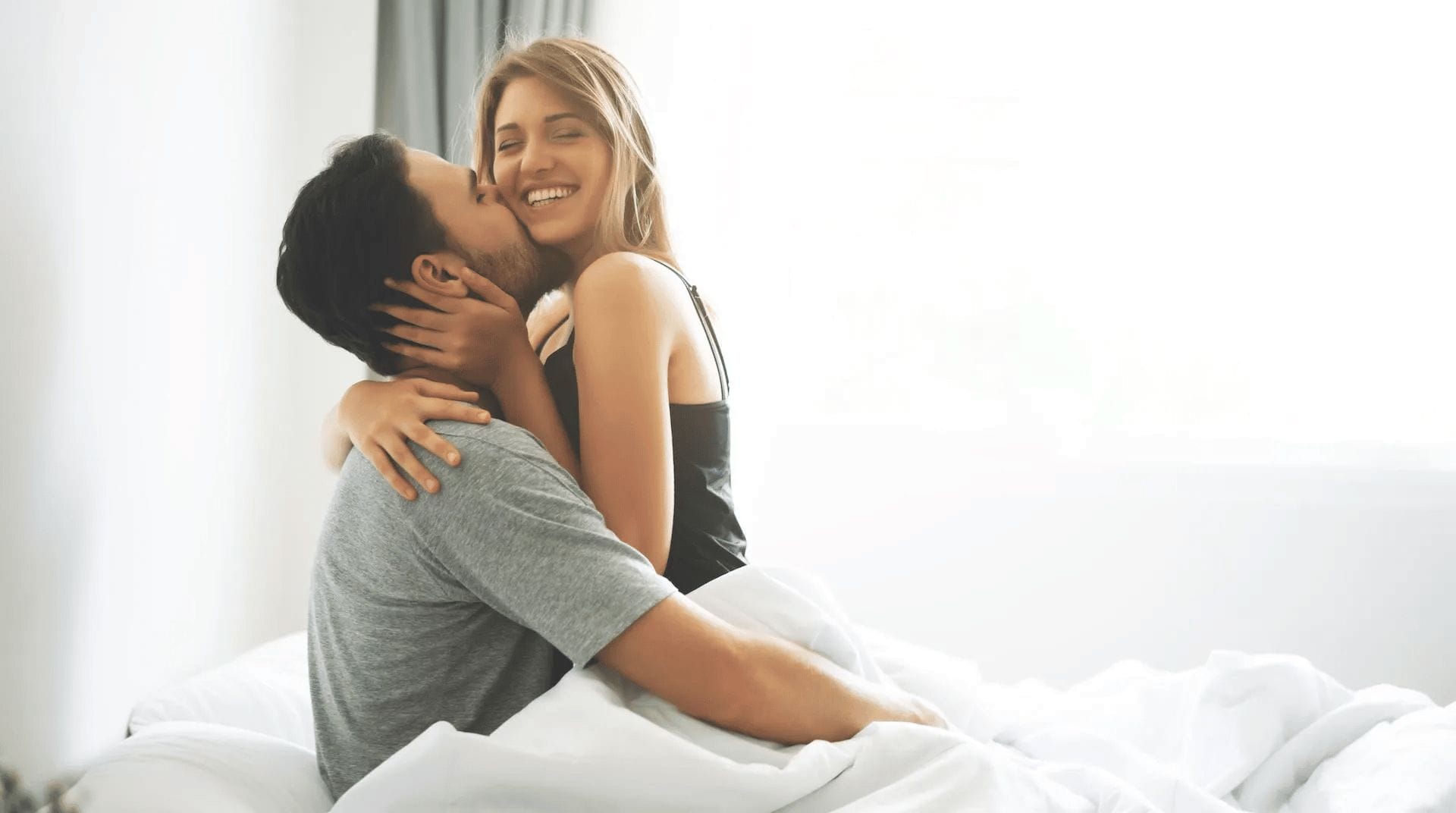 couple in bed smiling talking about how to get pregnant