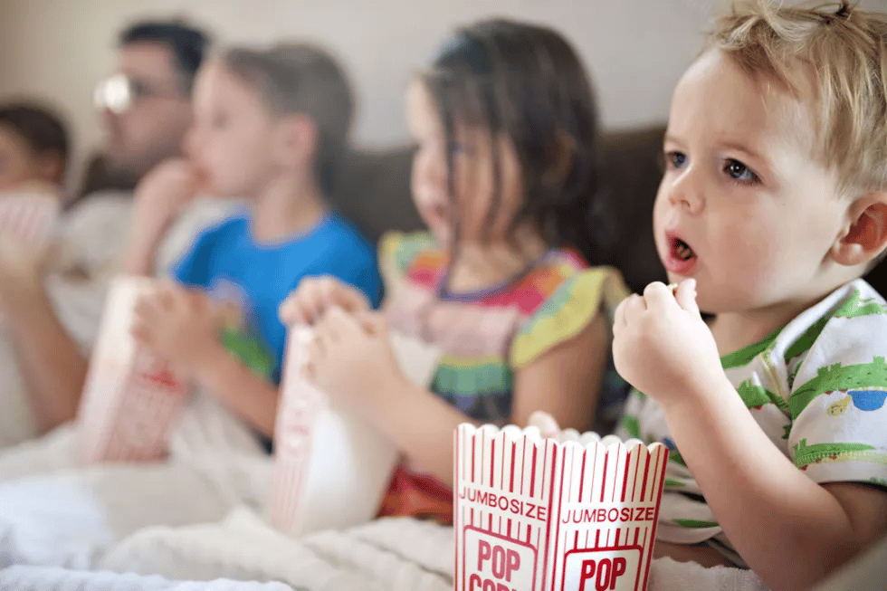 family sitting on couch eating popcorn watching movie- kids halloween movies