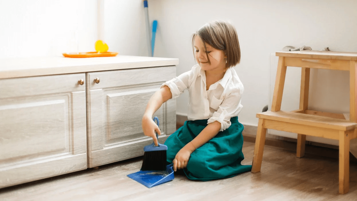 little girl using a handheld duster on the floor