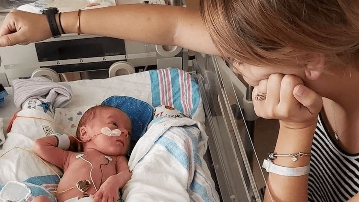 mom looking over baby in a hospital bed in a motherhood photo