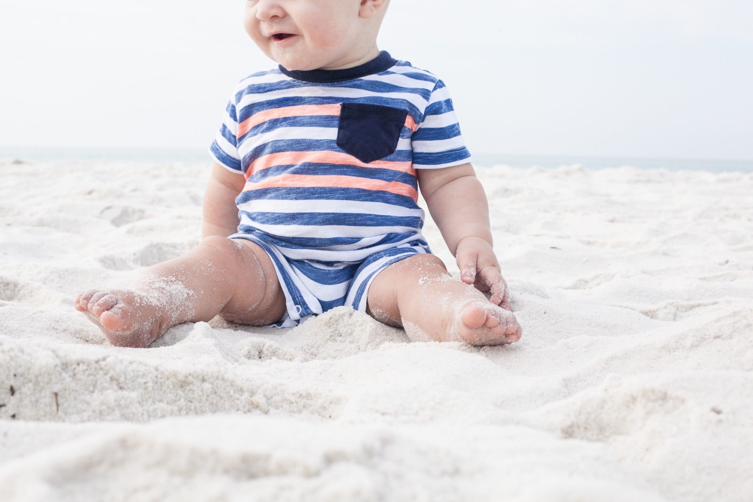 baby sitting in sand at beach - activities for 10-month-old