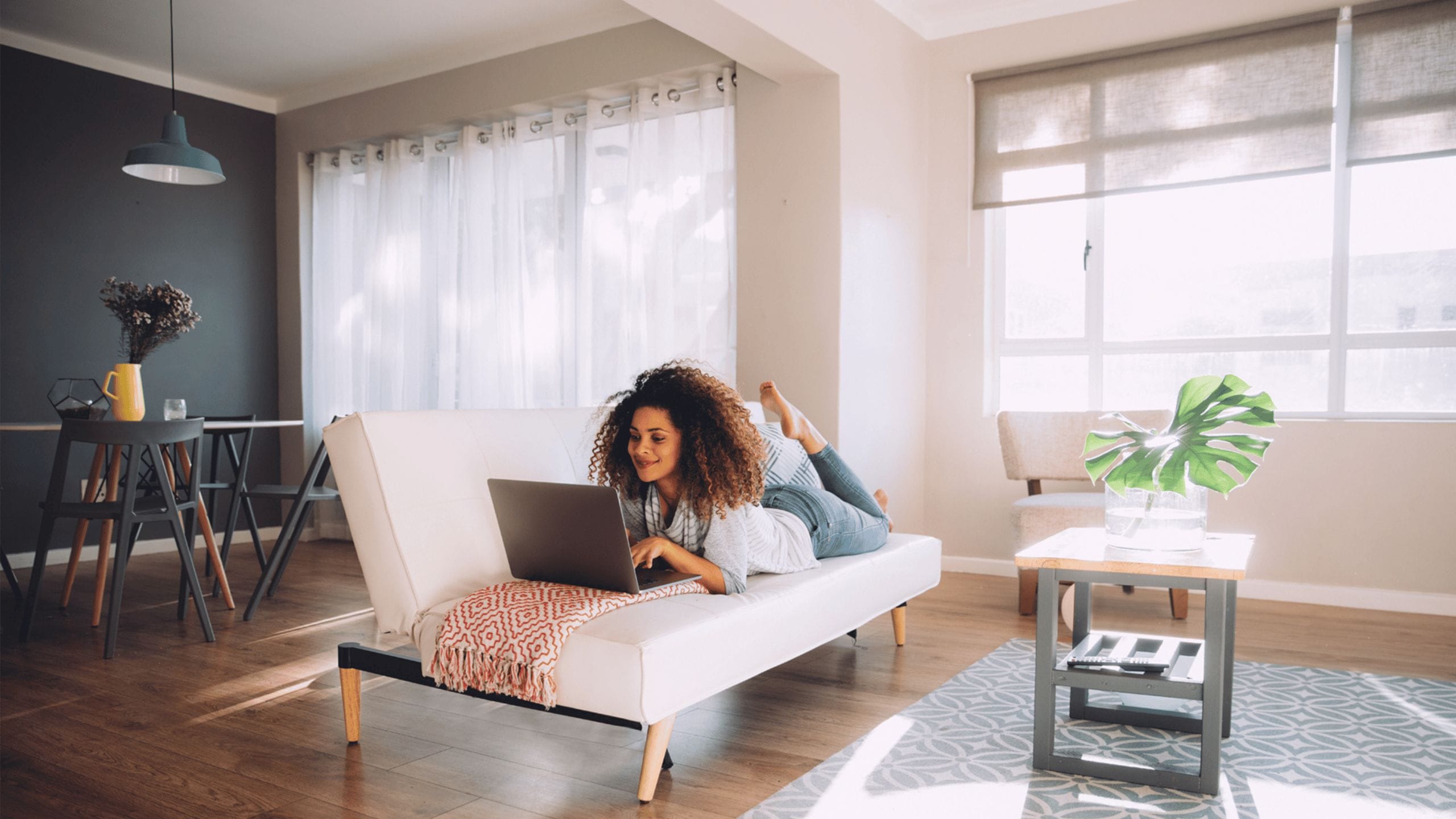 woman laying on the couch working on a computer