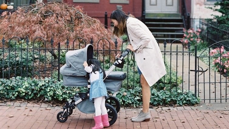 mom walking with daughter and baby in a stroller, preparing how to transition baby to daycare