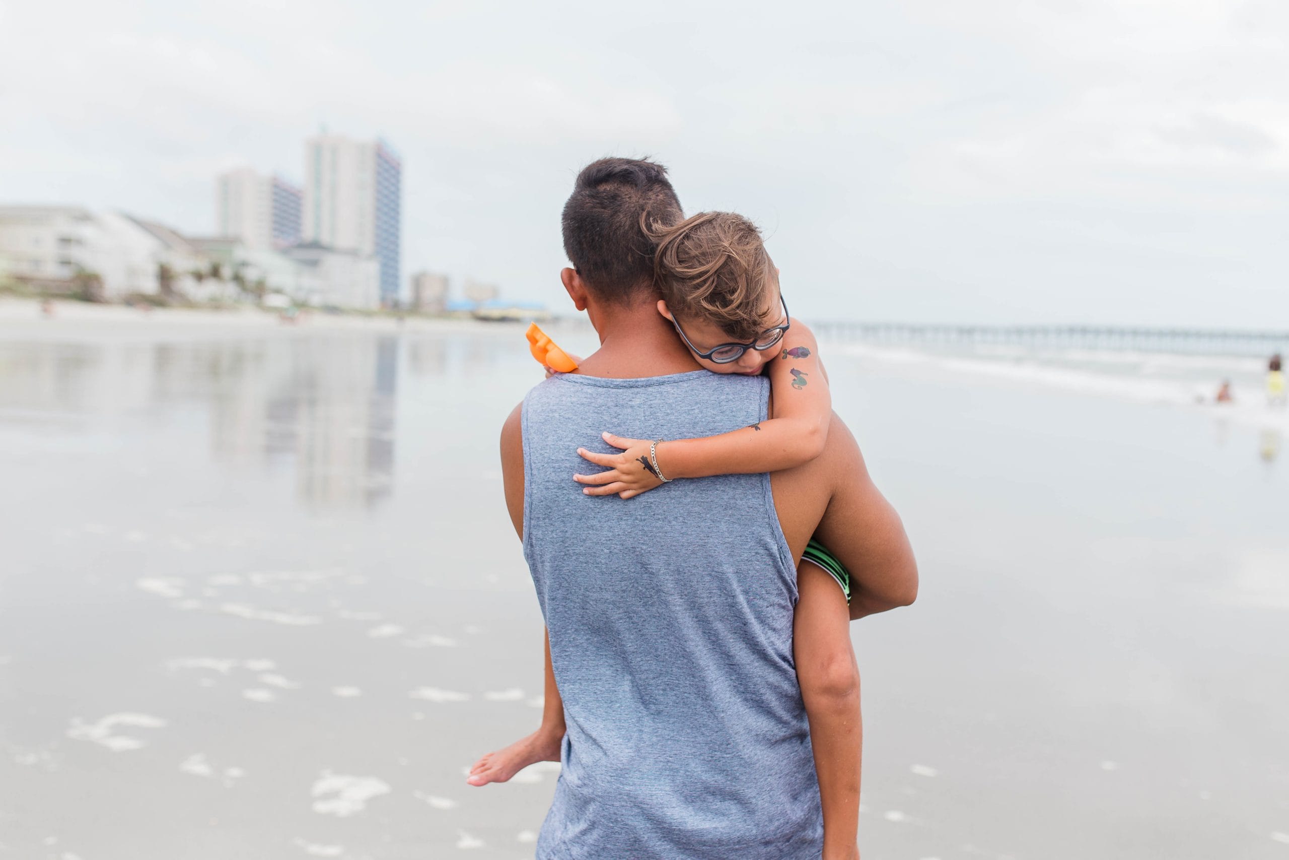 dad holding daughter while walking on the beach