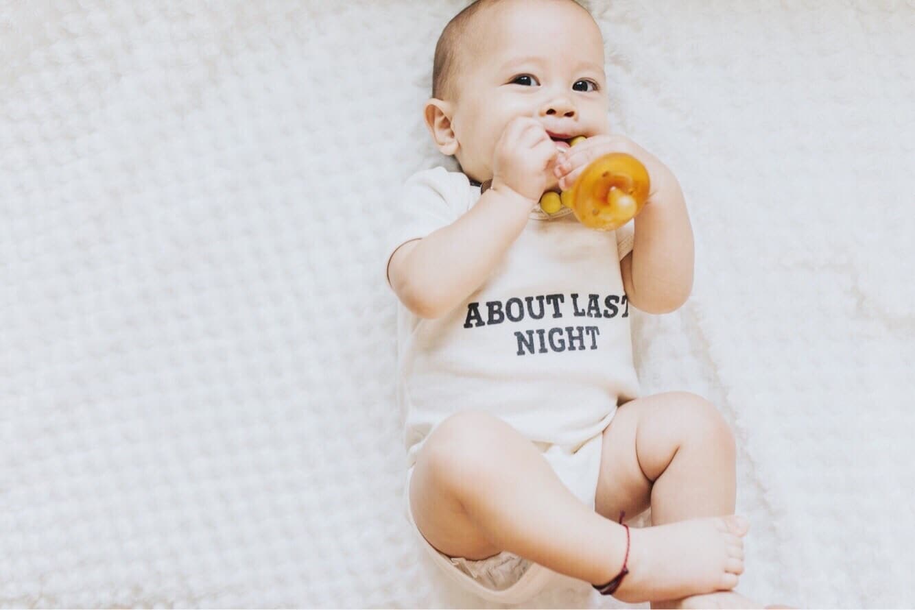 baby holding a pacifier laying down