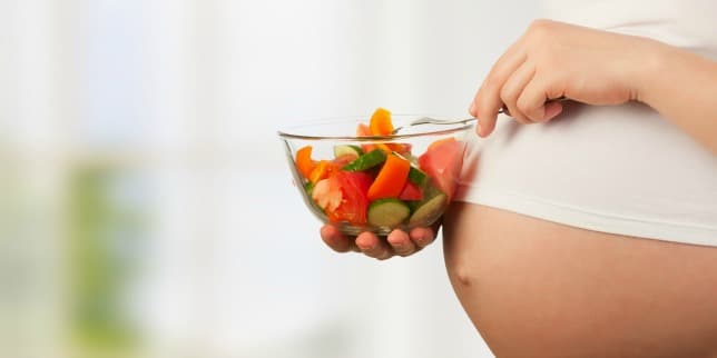 pregnant person holding bowl of fruit