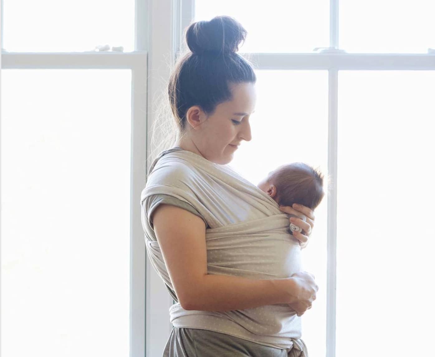 mom holding a newborn in a carrier