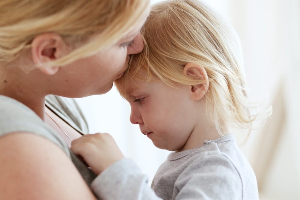 mom kissing daughter on head