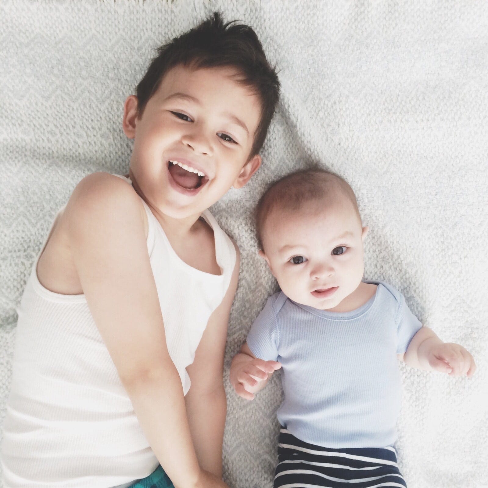 siblings laying in a bed together