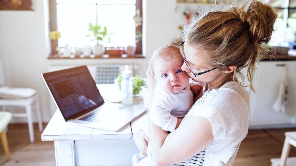 touched out: mother holding and kissing baby at home