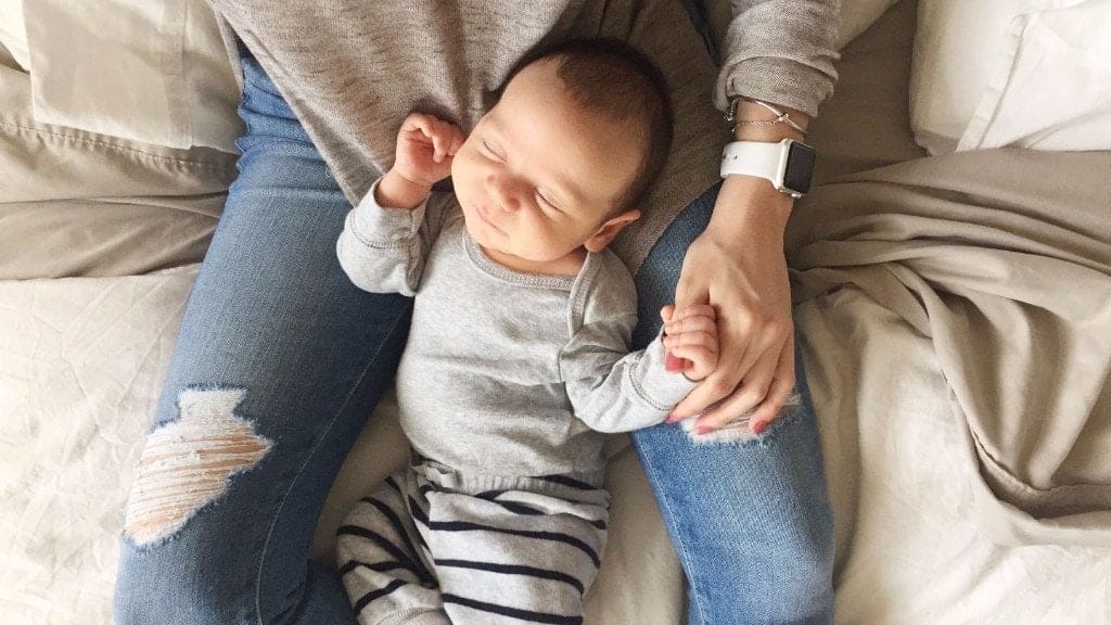 mom holding newborn between her legs