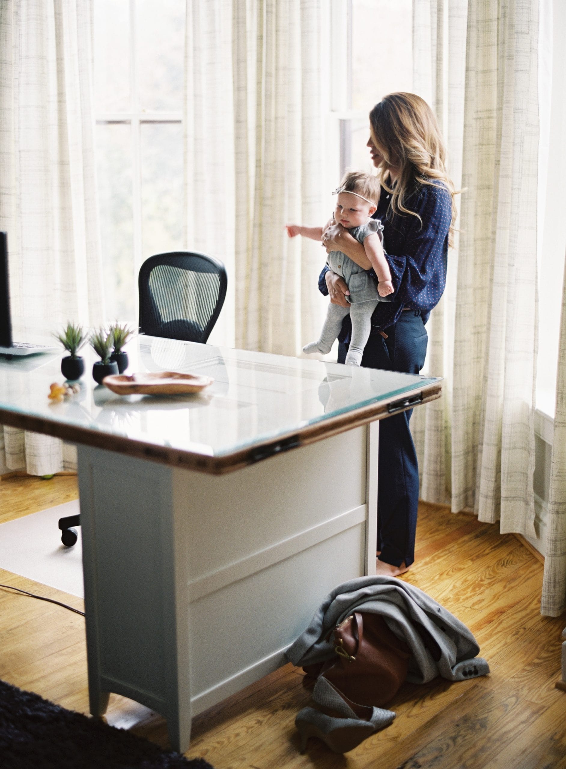 woman standing and holding toddler by desk