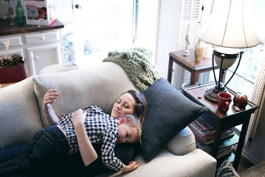 mom hugging child laying down on couch- benefits of being a working mom