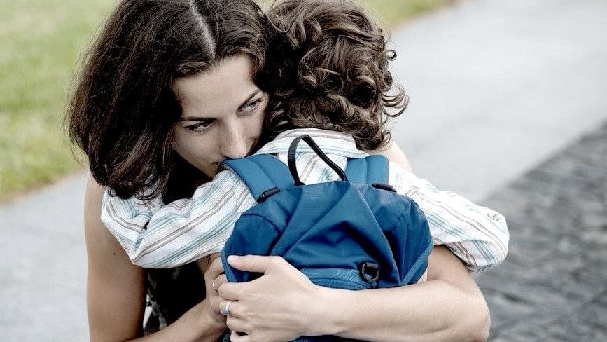 mom hugging a little boy wearing a backpack