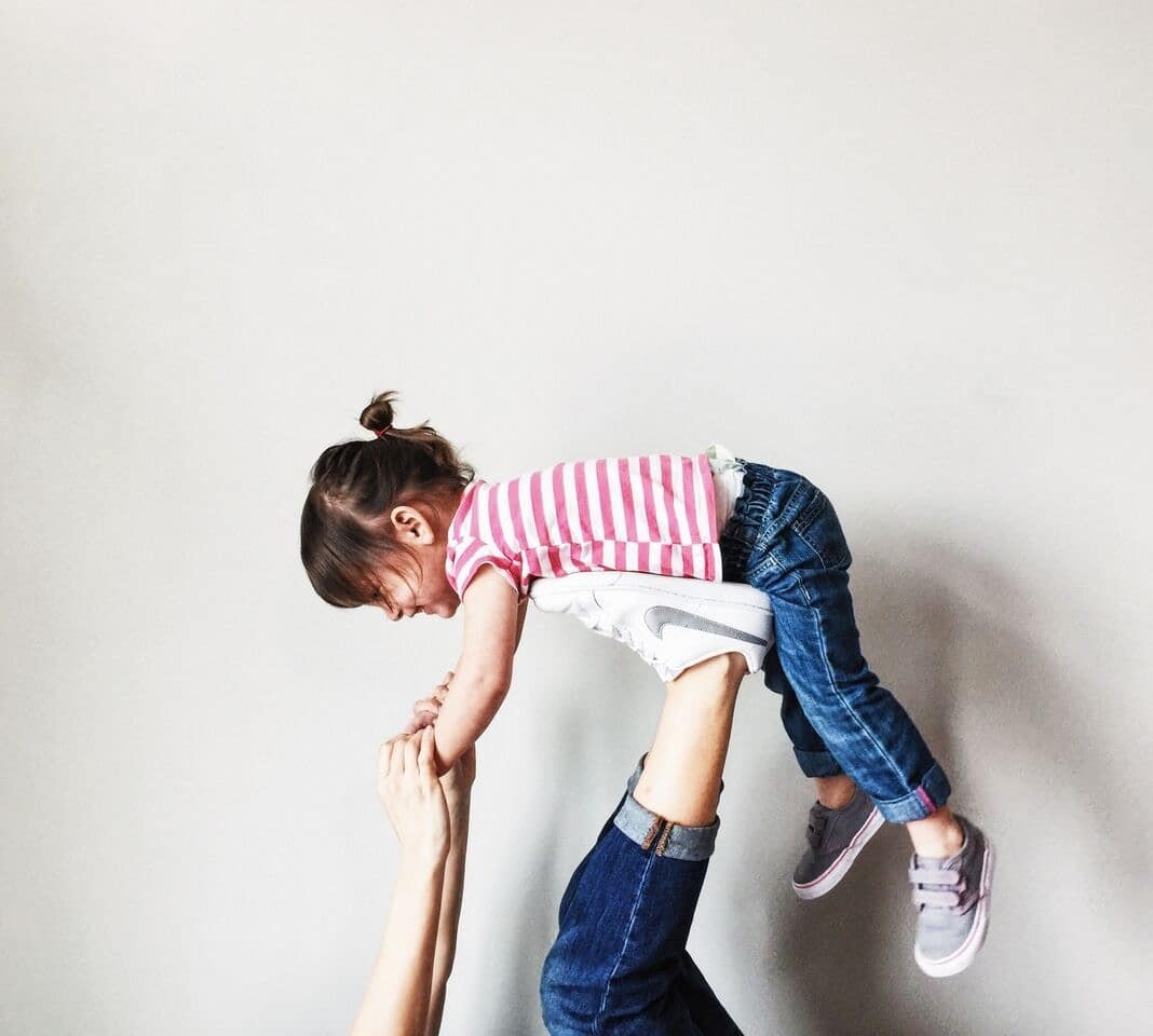 mom playing airplane with little girl