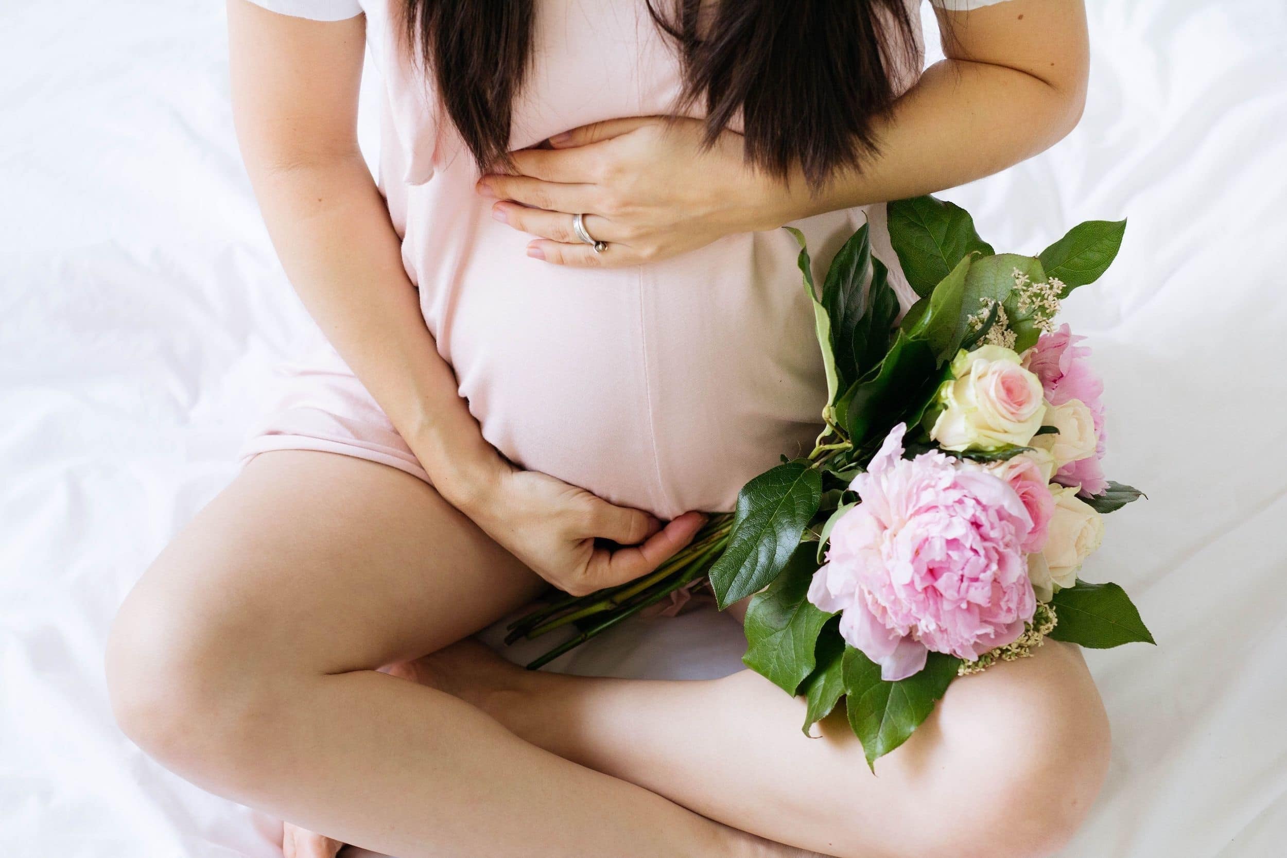 pregnant woman holding belly with flowers beside her