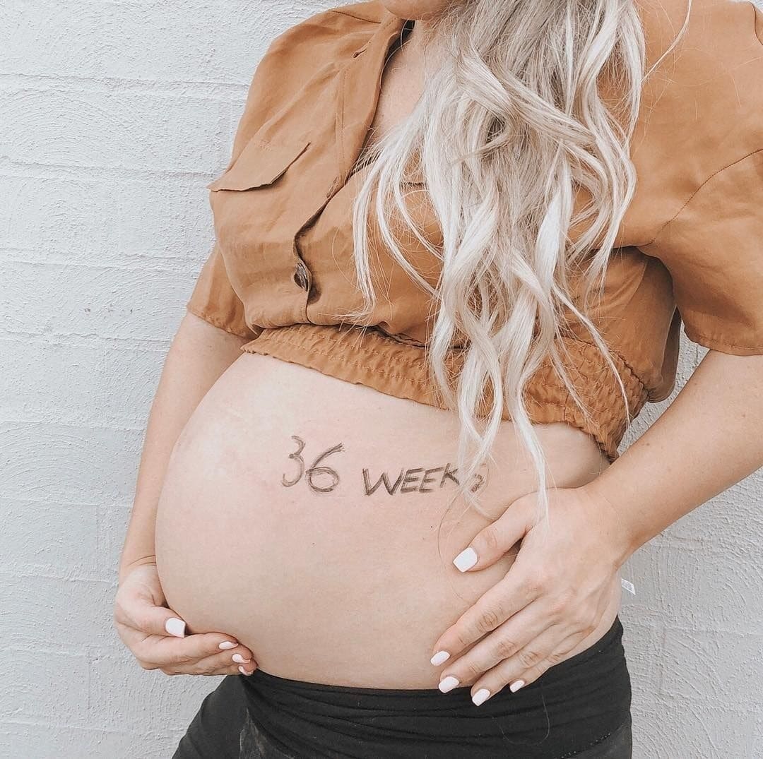 woman holding belly with 36 weeks written on it