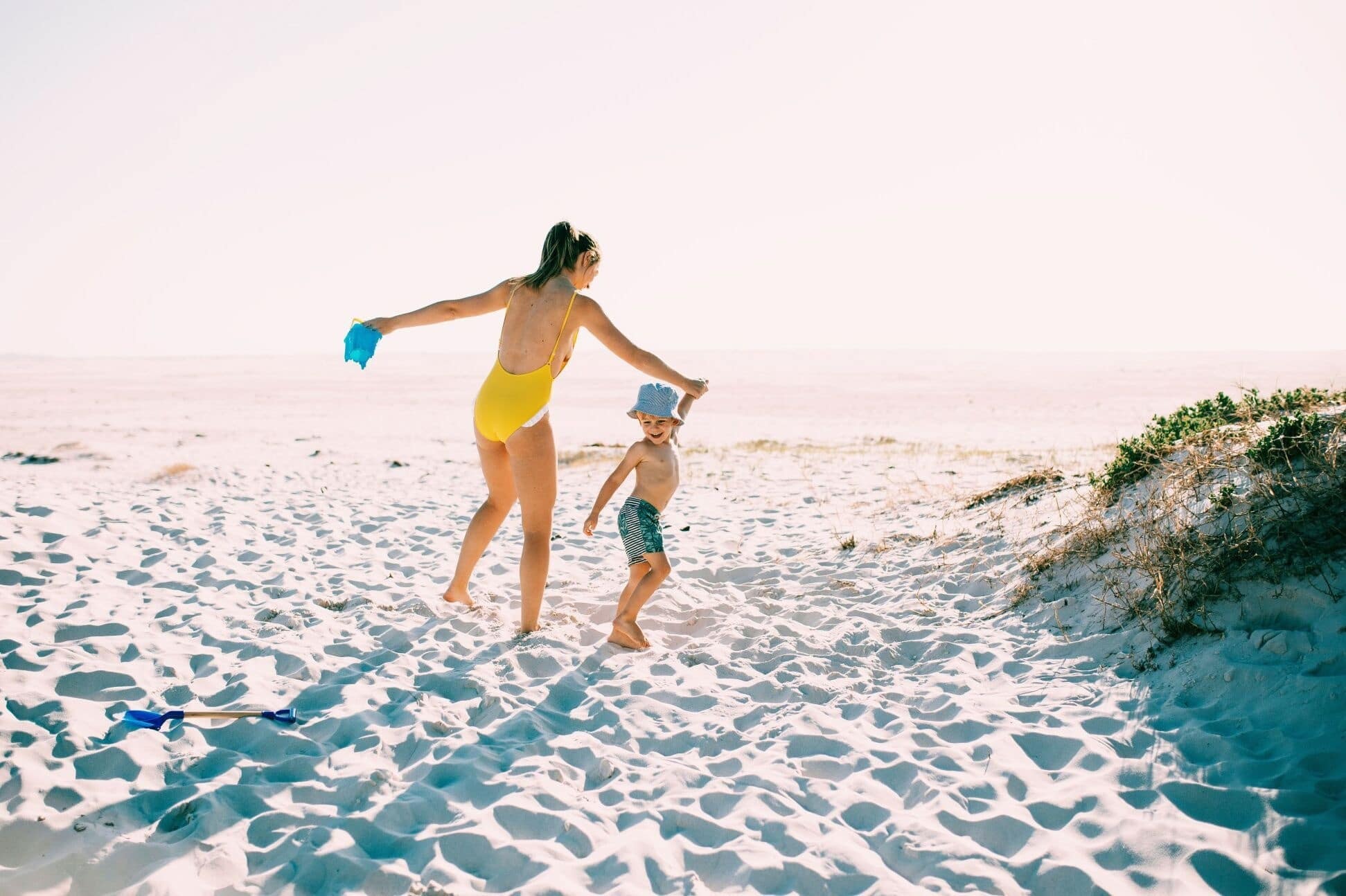 mom holding toddlers hand on the beach- how to relax on vacation with kids