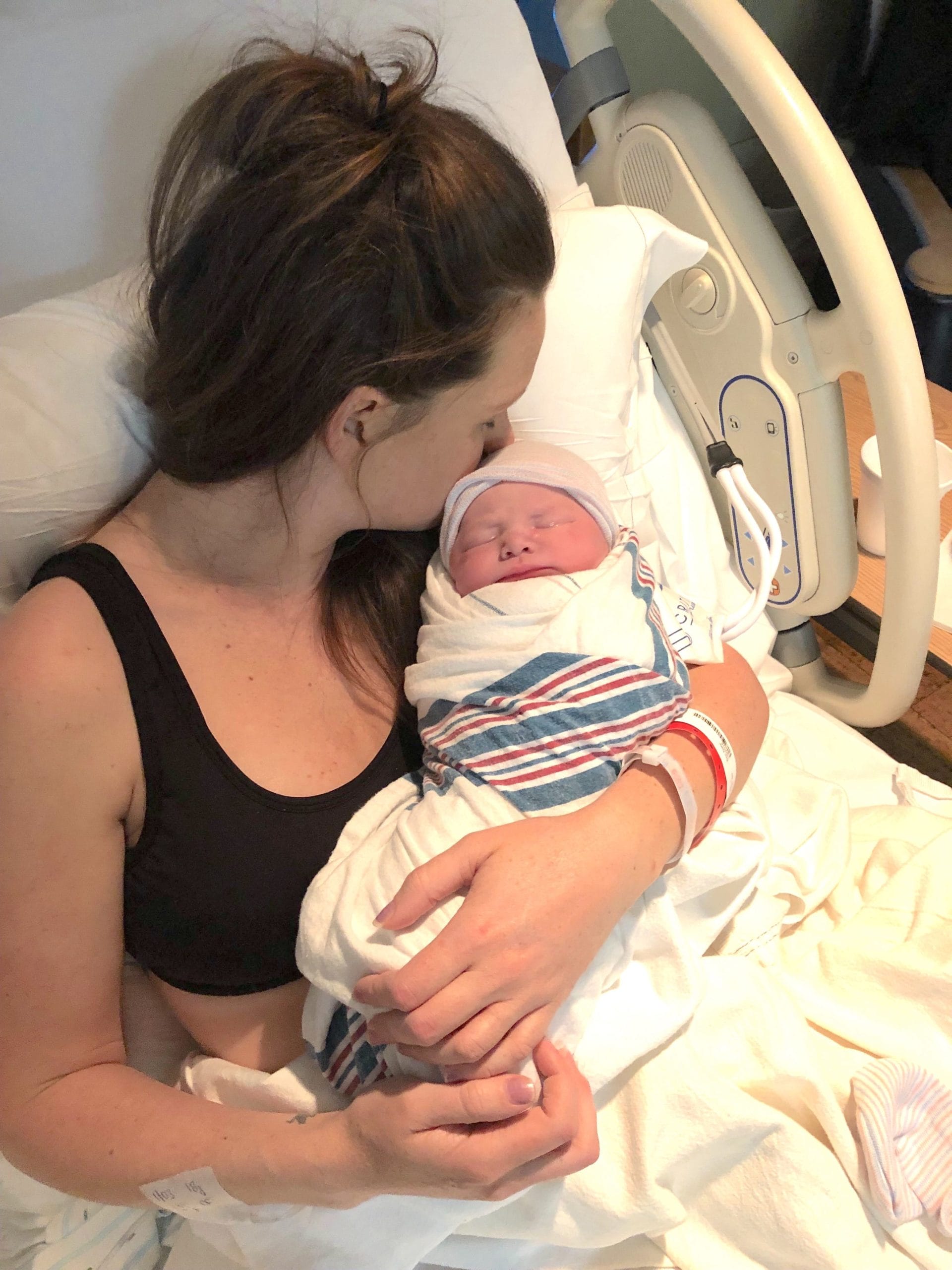 mom kissing newborn baby in the hospital after getting induced at 39 weeks