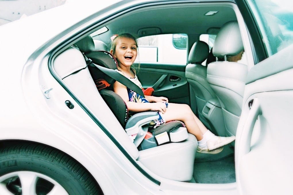 little girl sitting in booster seat in the car- how to make school mornings easier