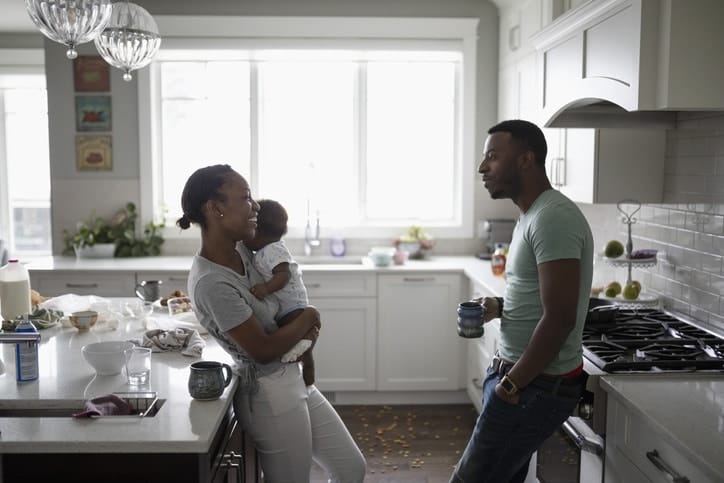 parents talking in the kitchen while mom holds baby