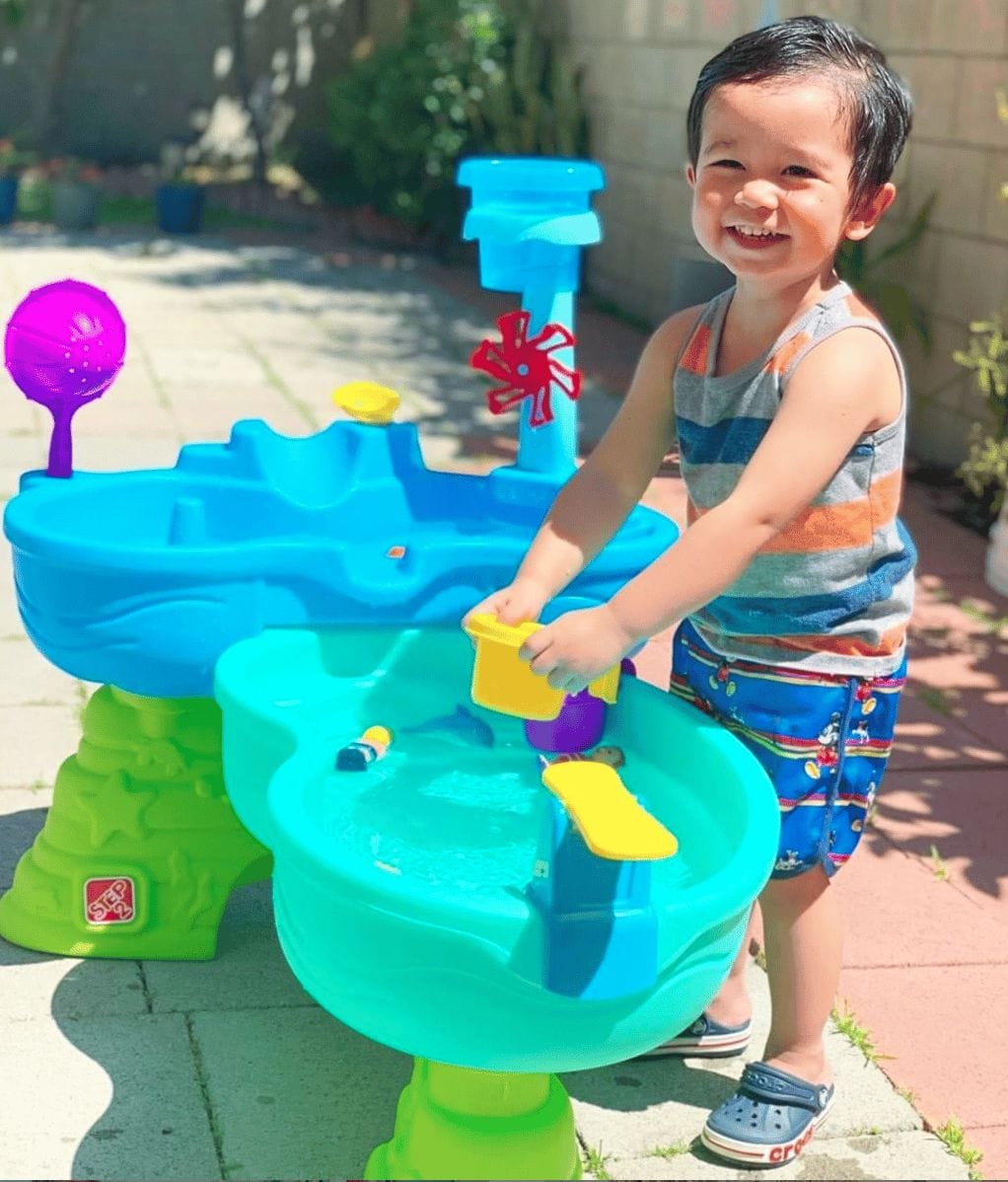 little boy playing with a water table